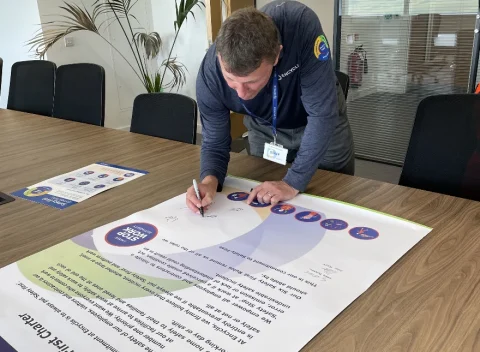 Person in Encyclis uniform signing a large document