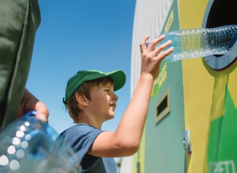 Child putting a plastic bottle in to recycling