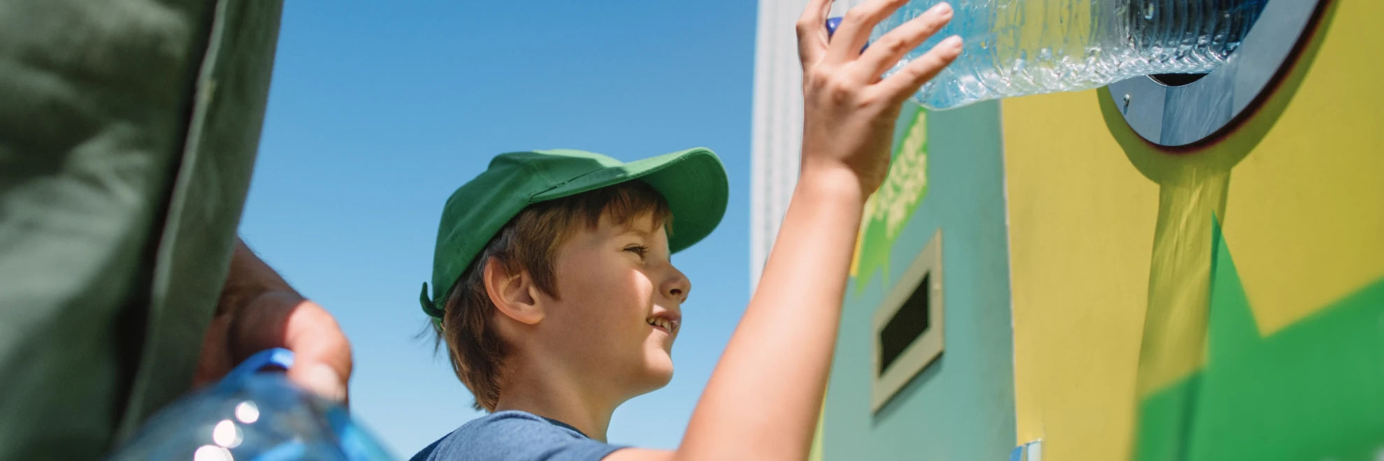 Young boy putting a plastic bottle in to a recycling plant
