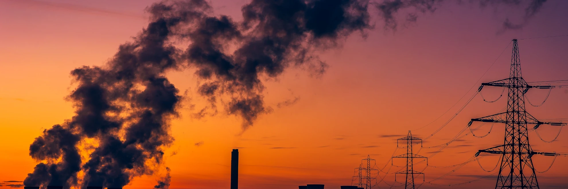 Smoke coming out of chimneys and power lines against a red sky