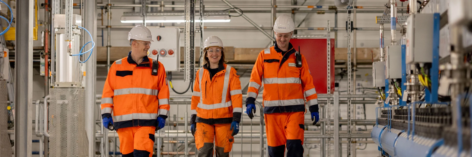 3 people walking side-by-side in a line in high vis.